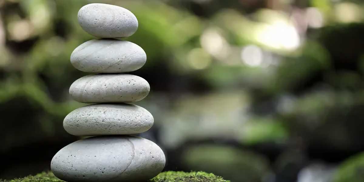 five smooth pebbles stacked in a tower in a verdant environment
